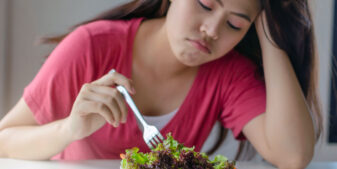 Orthorexic woman forcing herself to eat salad