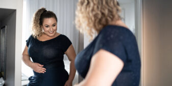 Full-figured woman admiring her clothes in mirror